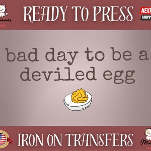 May include: Iron-on transfer design with the text "bad day to be a deviled egg" above an illustration of a deviled egg. The design includes the words "READY TO PRESS" and "IRON ON TRANSFERS".
