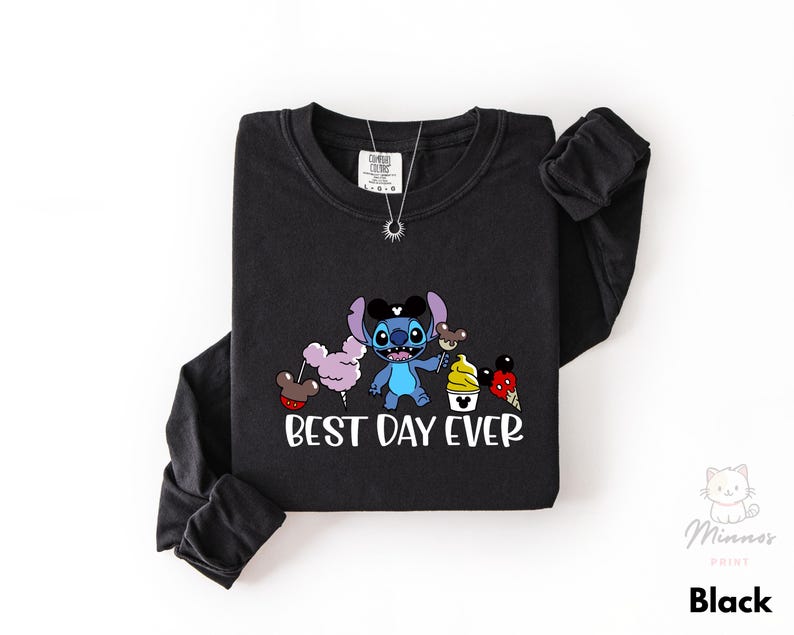 A black long-sleeved t-shirt with a graphic design featuring a cartoon character and the text "Best Day Ever" printed on it.