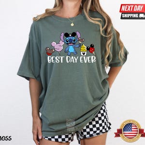 A woman wearing a green t-shirt with a cartoon character and text printed on it.