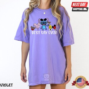 A person wearing a purple t-shirt with a cartoon character and text printed on it.