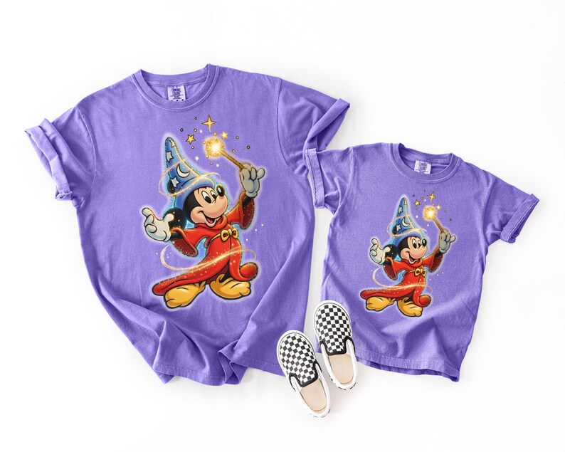 Peut inclure: Deux t-shirts violets, une taille adulte et une taille enfant, avec un dessin de Mickey Mouse en magicien avec une baguette. Les t-shirts sont assortis de chaussures &agrave; enfiler &agrave; carreaux noirs et blancs. Les t-shirts sont en mati&egrave;re souple.
