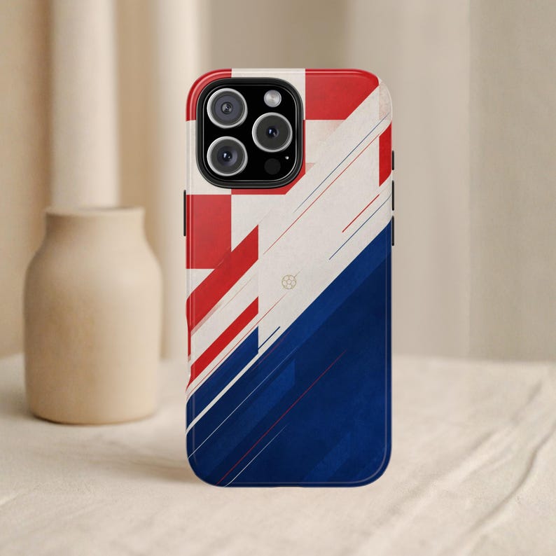 May include: A smartphone case with a geometric design in red, white, and blue. The top portion features a red and white pattern, while the bottom half is a deep blue. The case has a glossy finish and a camera cutout.