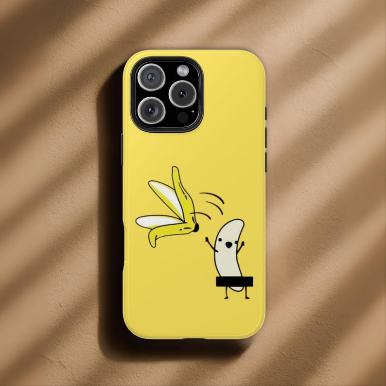 Może przedstawiać: Ż&oacute;łte etui na telefon z kresk&oacute;wkowym wzorem banana. Wz&oacute;r przedstawia obranego banana i banana z czarnym paskiem cenzury. Etui ma błyszczące wykończenie i wycięcie na aparat.