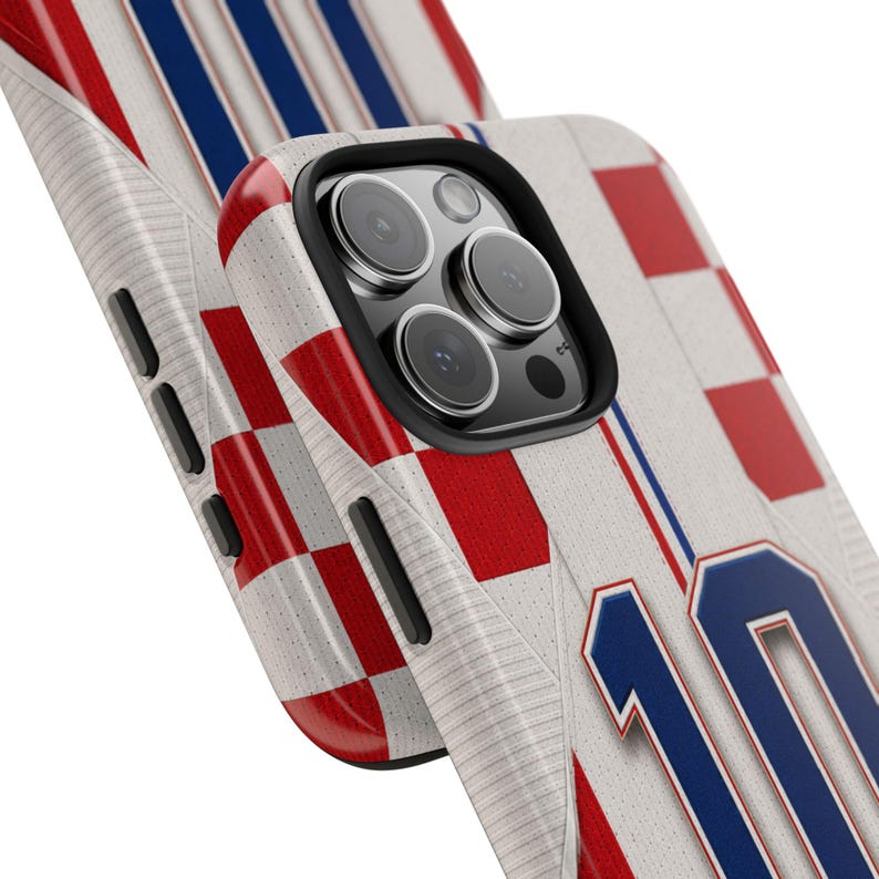 May include: A phone case featuring a design inspired by a sports jersey. The case has a white background with red and blue accents, including a checkered pattern and the number 10 in blue. The case is designed to fit a smartphone.