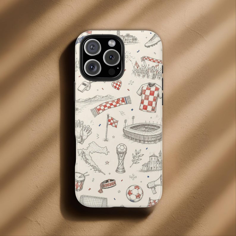 May include: A phone case with a cream background featuring a hand-drawn design of Croatian soccer-themed elements. The design includes a soccer ball, a checkered jersey, a stadium, a trophy, and a map of Croatia.