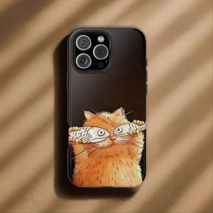 May include: A black smartphone case featuring a graphic illustration of a fluffy orange cat holding two white fish over its eyes. The cat has a small pink nose and long whiskers, set against a dark background with a triple camera lens cutout.