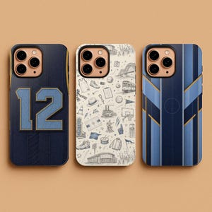 May include: Three smartphone cases with distinct designs. The left case is dark blue with the number 12 in light blue. The center case is cream with various small sketches of sports and city icons. The right case features vertical blue stripes.