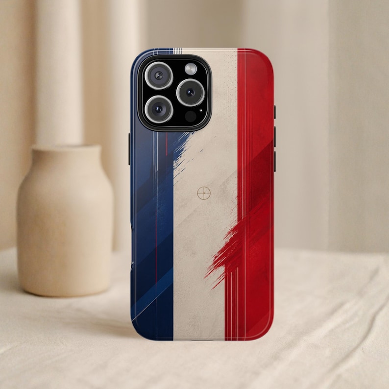 May include: A phone case featuring the French flag design. The case has a blue border and a tricolor design of blue, white, and red. The design has a distressed, brushstroke effect. The phone case has a camera cutout with three lenses.
