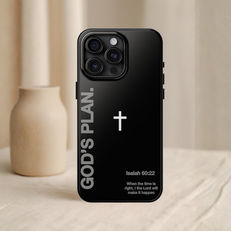 May include: Black phone case with the text "GOD'S PLAN." and a white cross. Below the cross is the text "Isaiah 60:22" and a quote. The phone case is on a neutral background.