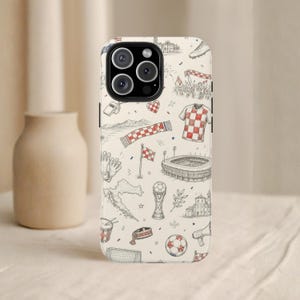May include: A phone case with a cream background and a repeating pattern of Croatian soccer-themed illustrations in black and red. The design includes a soccer ball, stadium, jersey, and flag.