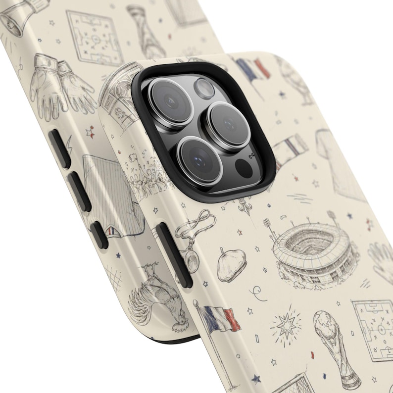 May include: A phone case with a cream-colored background featuring a repeating pattern of hand-drawn illustrations. The drawings include a soccer stadium, a rooster, a French flag, and other sports-related imagery. The case has a black border around the camera.