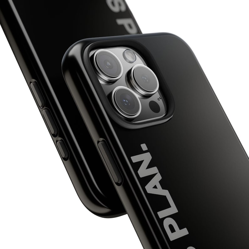 May include: Black phone case with the word "PLAN." printed in white. The case has a glossy finish and a raised edge around the camera lenses. The phone's camera lenses are visible.