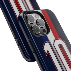 May include: Close-up of a navy blue phone case with white and red stripes, and the number 10 in white. The case has a black border and a camera lens cutout. The design resembles a sports jersey.