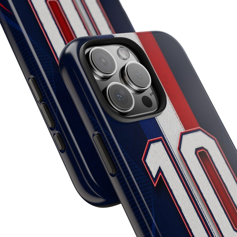 May include: Close-up of a navy blue phone case with white and red stripes, and the number 10 in white. The case has a black border and a camera lens cutout. The design resembles a sports jersey.