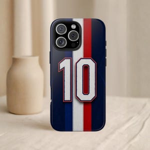 May include: A navy blue phone case with a vertical white, red, and white stripe design. The number "10" is prominently displayed in white with a red outline. The case has a glossy finish and a camera cutout.