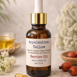 May include: A brown glass bottle of Appalachian Tallow Barrier Oil with a gold cap and white dropper. The label lists ingredients like Jojoba Oil and Vitamin E. The bottle is 1 fl oz.
