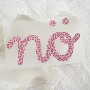 Könnte beinhalten: Ein Vinyl-Aufkleber mit dem Wort "nö" in einer geschwungenen Handschrift-Schriftart. Die Buchstaben und die zwei Punkte über dem "o" sind mit einem rosa und dunkelrosa Leopardenmuster auf einer transparenten, rechteckigen Klebefolie gefüllt.