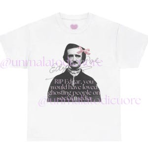 Può includere: T-shirt bianca con un ritratto in bianco e nero di Edgar Allan Poe, ornato da un fiocco rosa. La maglietta include il testo: "RIP Edgar, you would have loved ghosting people on social media."