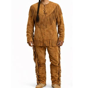 May include: A brown suede outfit featuring a long-sleeved shirt and pants, both adorned with fringe detailing. The shirt has a laced neckline. The outfit is a traditional style, suitable for costumes or themed events.