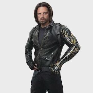 May include: A black leather jacket with a zip, worn over a black top. The jacket has a small pocket on the chest. The person is wearing black trousers and a black belt. The left arm is a metallic gold and black prosthetic.