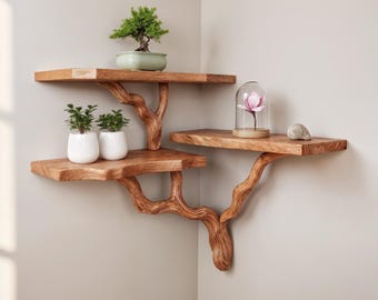 May include: Wooden corner shelves with a unique tree branch design. The shelves are stained a warm brown and hold a bonsai tree, two small potted plants, a decorative flower under a glass dome, and a seashell. The shelves are mounted on a neutral-colored wall.