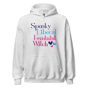 May include: A light gray hooded sweatshirt with the words "Spooky Liberal Feminist Witch" in a mix of purple, blue, and pink lettering. The design includes heart shapes.