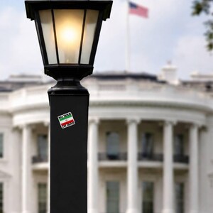 No War On Iran vinyl decal applied to black lamp post with White House in background, anti war political protest sticker