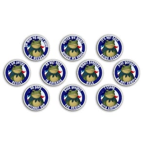 May include: A collection of ten circular stickers featuring a cartoon frog wearing a cape. Each sticker has a blue border and white text with phrases like "I Am Antifa Resist" and "United We Ribbit".