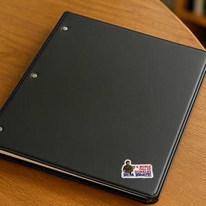 In a World Full of Donalds Be a Bruce political vinyl sticker on black binder progressive protest office decor
