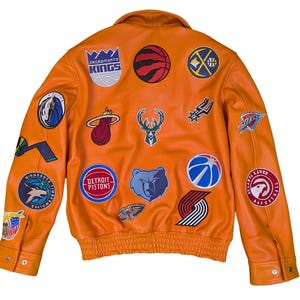 May include: Orange leather jacket with multiple team logo patches. Patches include the Sacramento Kings, Detroit Pistons, and Miami Heat. The jacket has a button closure and a ribbed hem.