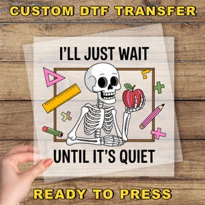 May include: A DTF transfer featuring a skeleton holding an apple, surrounded by school-themed graphics. Text reads "I'll Just Wait Until It's Quiet" and "Ready to Press". The design includes a ruler, pencil, and geometric shapes.