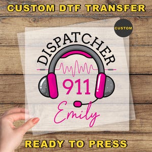May include: A custom DTF transfer featuring the word "DISPATCHER" above a headset design with a pink and gray color scheme. The number "911" is in the center, with the name "Emily" below. The words "READY TO PRESS" are at the bottom.