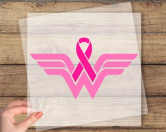 May include: A pink breast cancer awareness ribbon and wings design on a clear transfer sheet. The design is in the shape of a "W" with wings, and the text "CUSTOM DTF TRANSFER" and "READY TO PRESS" are in yellow.