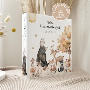 Puede incluir: Una carpeta blanca con el texto "Meine Kindergartenzeit" y "Luis Muster". La portada presenta una ilustración de animales del bosque, incluyendo un oso, un ciervo, un zorro y un búho, en estilo acuarela.