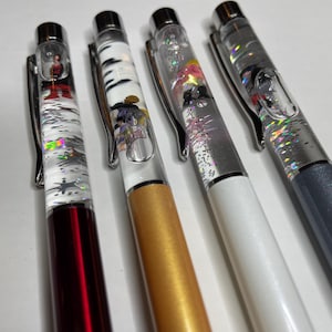 May include: Four clear liquid-filled pens with glitter and colorful designs. The pens have silver caps and different colored barrels: red, gold, white, and gray.