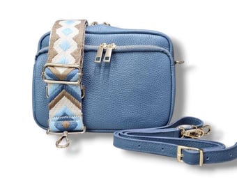 May include: A blue leather crossbody bag with a gold zipper and a patterned strap. The bag has a small pocket on the front and a long adjustable strap.