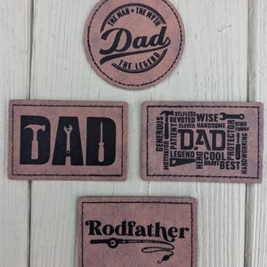 May include: Three brown leather patches with black text. The first patch is round and says "The Man - The Myth - Dad - The Legend". The second patch is rectangular and says "DAD" with a hammer, wrench, and screwdriver. The third patch is rectangular and says "Rodfather" with a fishing rod and hook.