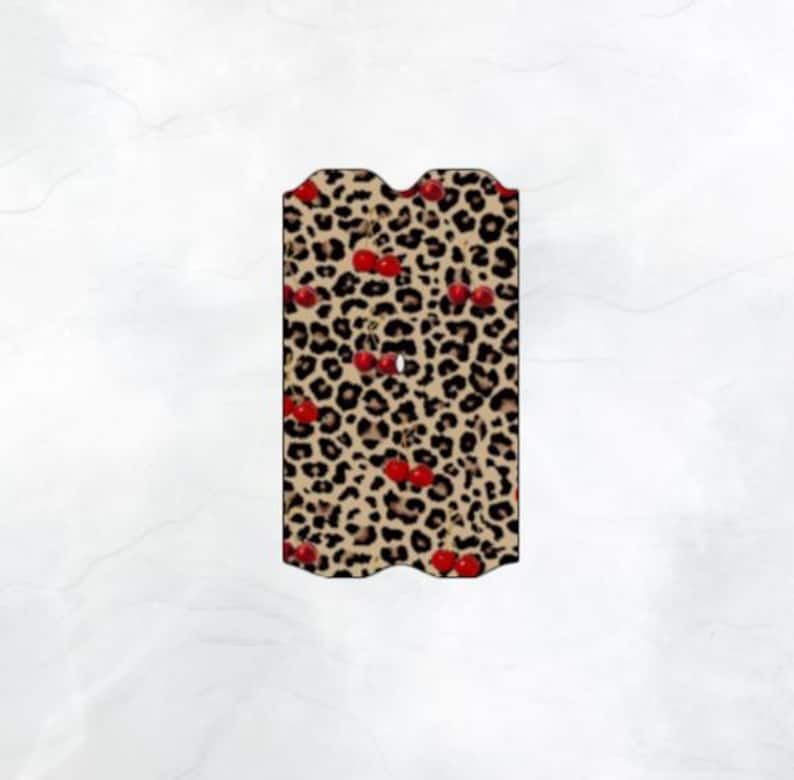May include: A brown and tan leopard print pattern with red cherries. The pattern is on a phone case with a wavy edge.