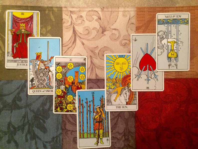 May include: A collection of tarot cards, including "Justice," "Queen of Swords," "Ten of Pentacles," "The Sun," "Three of Swords," "Ace of Cups," and "Nine of Wands." The cards are arranged on a patterned surface with a mix of colors and designs.