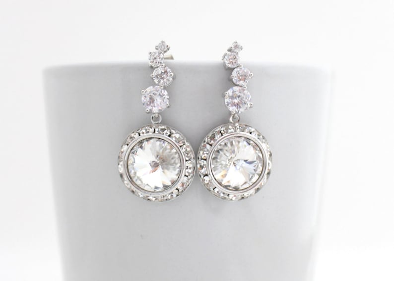 May include: Silver dangle earrings with a large clear crystal surrounded by smaller crystals.