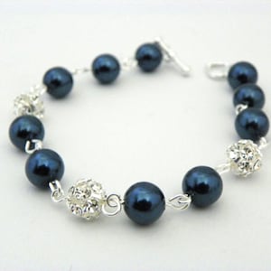 May include: A bracelet featuring dark blue, round beads interspersed with sparkling, silver-toned crystal accents. The bracelet is strung on a silver chain and has a simple clasp.