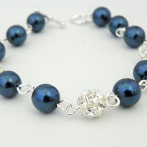 May include: A bracelet featuring navy blue faux pearls and sparkling crystal-covered beads. The beads are strung together with silver-colored chain links and a clasp. This jewelry item is suitable for special occasions.