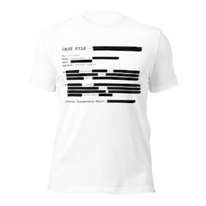 Può includere: T-shirt bianca con testo nero che simula un documento oscurato. Il testo include "CASE FILE", "Status Update" e "Internal Transparency Report". La maglietta ha un girocollo e maniche corte.