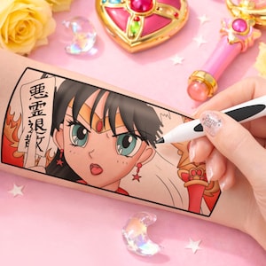 May include: A temporary tattoo featuring a manga-style illustration of a female character with teal eyes and black hair. The tattoo is being drawn on with a black pen. The background includes a pink surface, decorative items, and text.