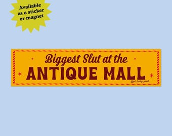 May include: A rectangular yellow sticker or magnet featuring a red border with a wavy line pattern and small star accents. The text reads Biggest Slut at the ANTIQUE MALL in dark red lettering, with the small handle get_lucky_goods in the corner.