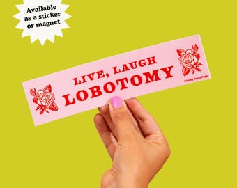 May include: A rectangular pink sticker featuring the red text "LIVE, LAUGH LOBOTOMY" in a bold serif font. The design includes a red rose illustration on both the left and right sides of the text. The sticker has a smooth, matte finish.