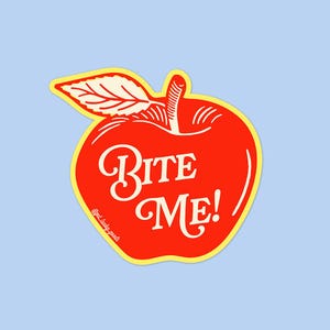 May include: A die-cut sticker shaped like a bright red apple with a yellow border. The apple features a white leaf and stem at the top. Centered on the apple is the white text "BITE ME!" in a decorative script font. Small text reads "@get.lucky.goods".