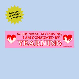 May include: A pink bumper sticker with the text "SORRY ABOUT MY DRIVING, I AM CONSUMED BY YEARNING" in red and white. The sticker features a heart with flames on each end and a yellow starburst that says "Available as a sticker or magnet."