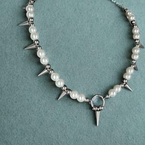Punk pearl spike choker necklace with stainless steel beads on display stand