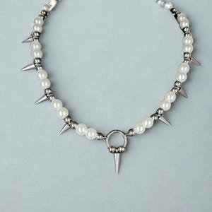 Gothic punk choker with metal spikes and imitation pearls on flat surface